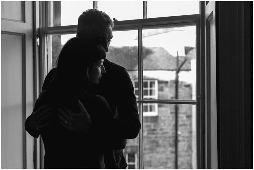 Couple embrace by the window in their apartment 