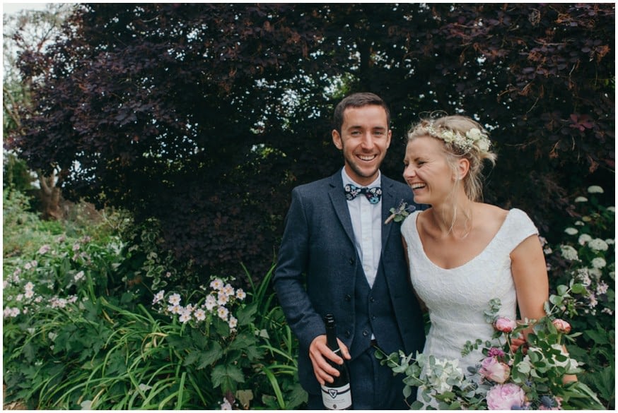 Boho Bride and Groom laugh surrounded by flowers